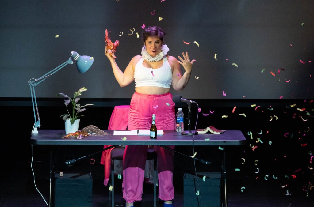 woman wearing neck cuff onstage surrounded by confetti