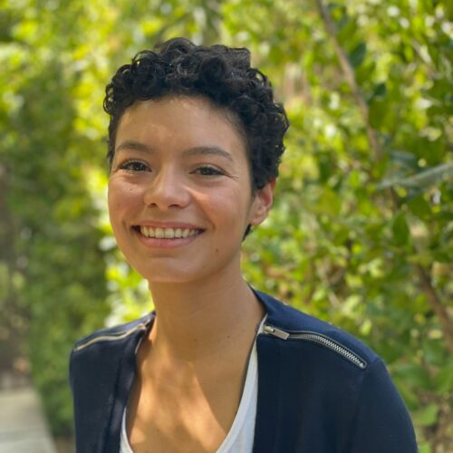 woman smiling in front of a backdrop of green trees