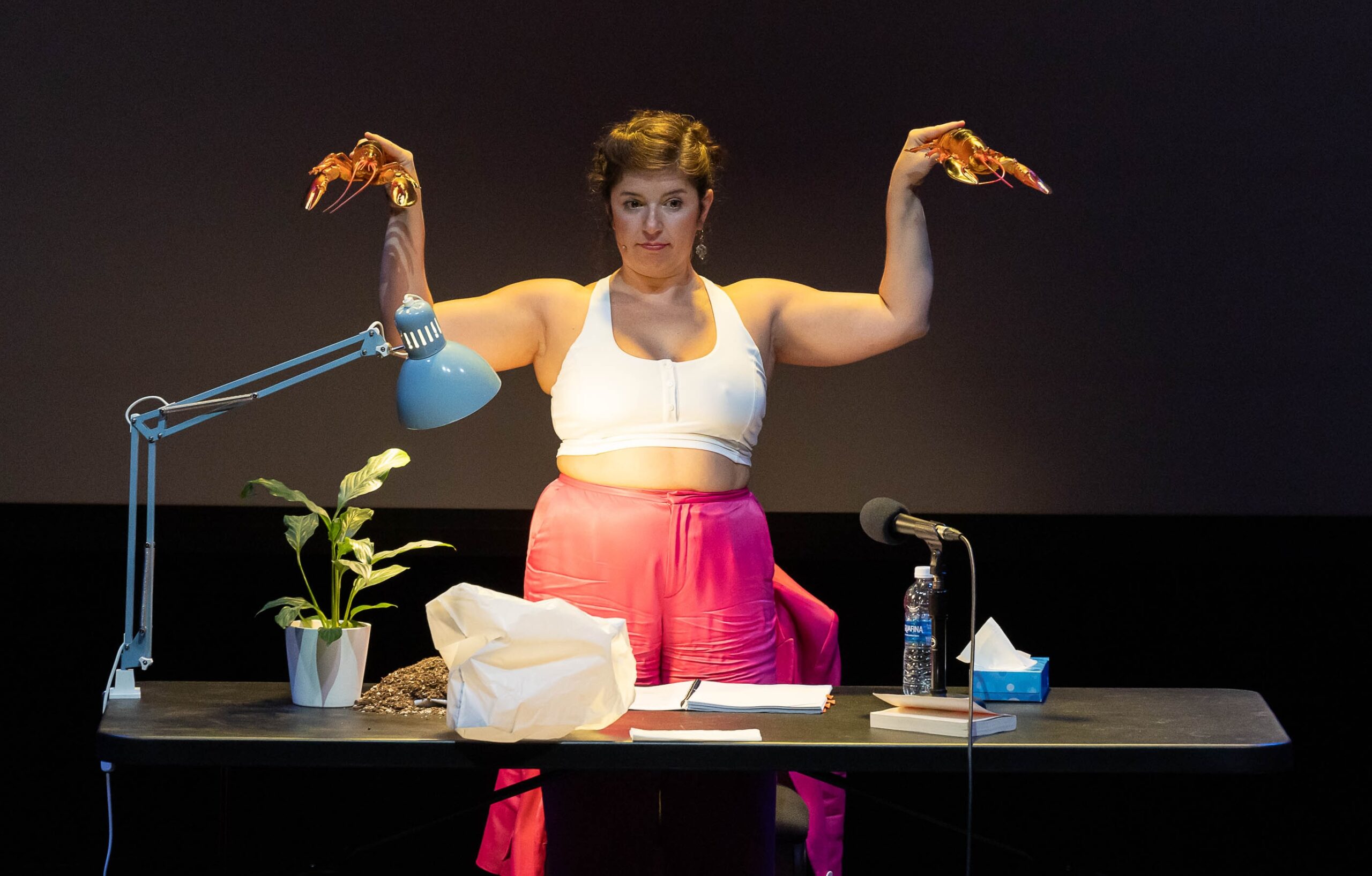 Theater actress on stage holding fake lobsters in her hands