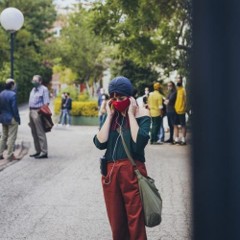 Image of someone with a face mask and with headphones on in a public setting. 