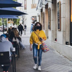 Image of someone walking through the streets with a face mask on.