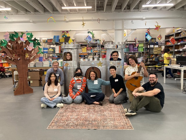 group of people sitting and posing in front of a children's theater prop castle