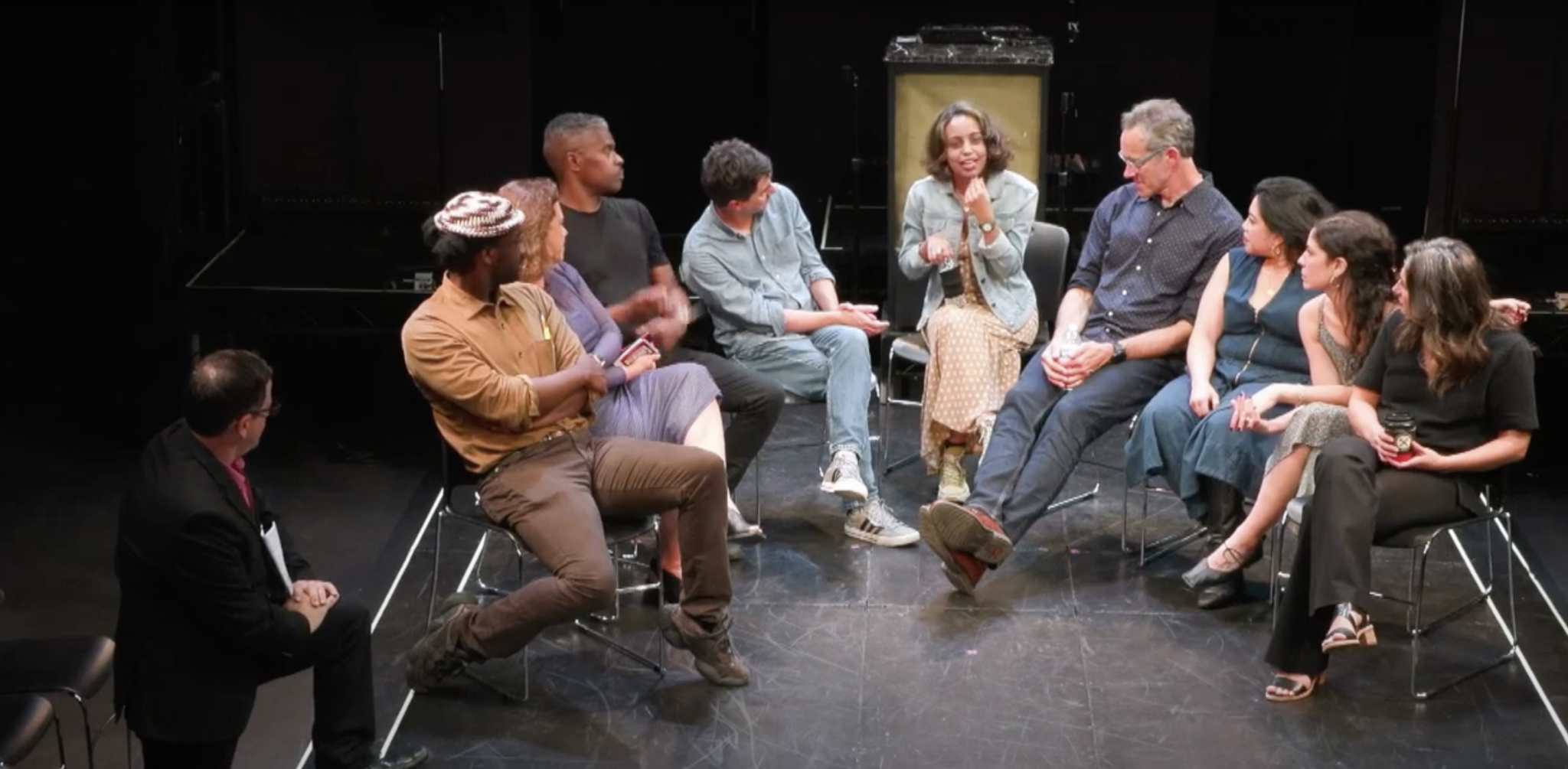 group of people sitting in a circle onstage